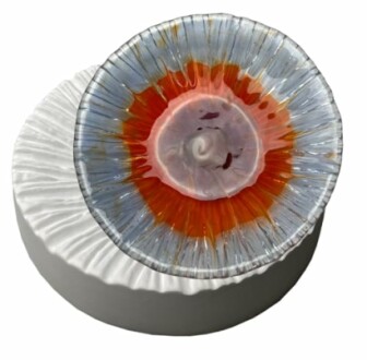 Circular glass art piece with vibrant colors on a white base