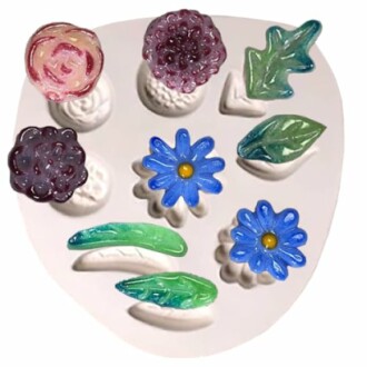 Colorful glass flower and leaf molds on a white surface.