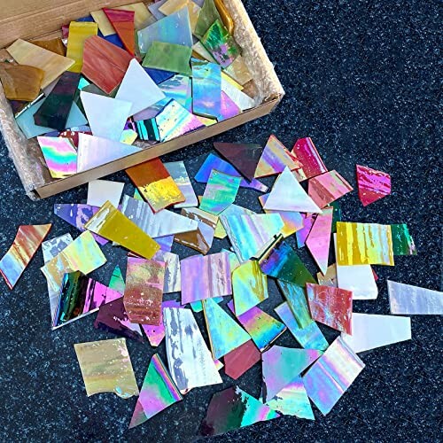 Assorted colorful iridescent glass tiles scattered on a dark surface.