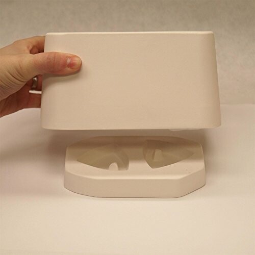 Hand holding a white ceramic cover above a base.