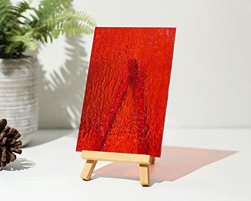 Red textured glass panel displayed on a small wooden easel.